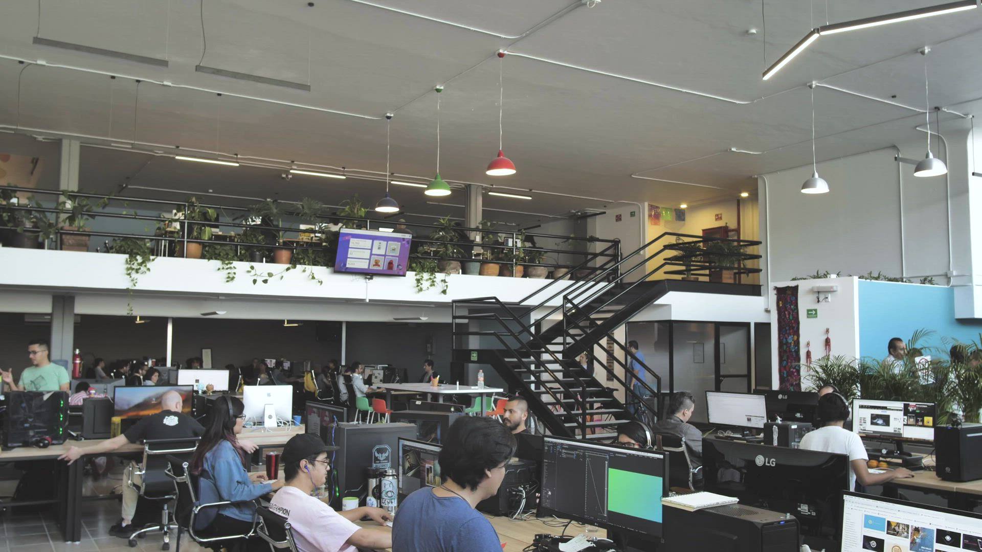 Una oficina abierta y concurrida, con personas trabajando en sus escritorios