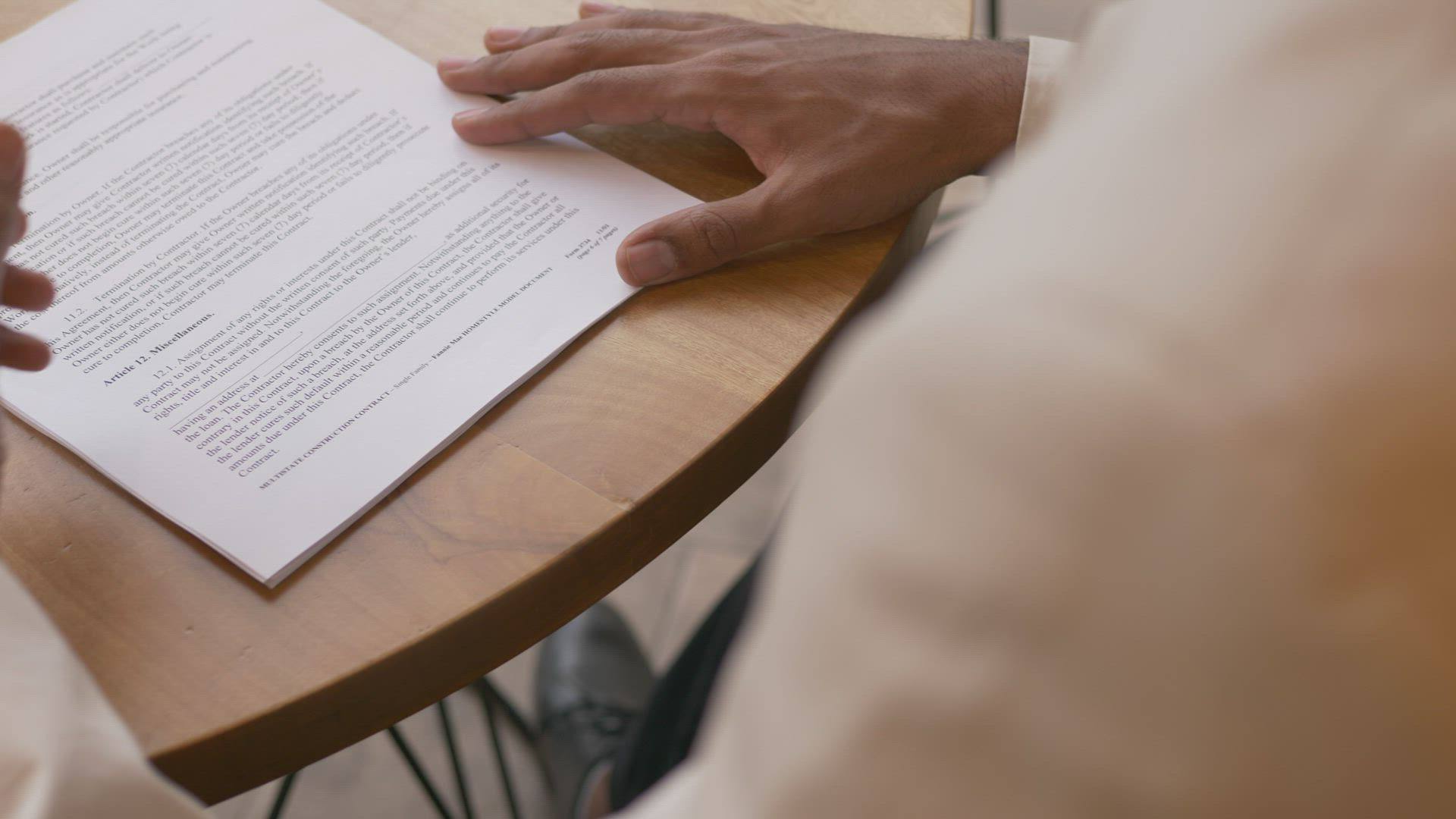 Dos personas revisan un contrato impreso en una mesa de madera